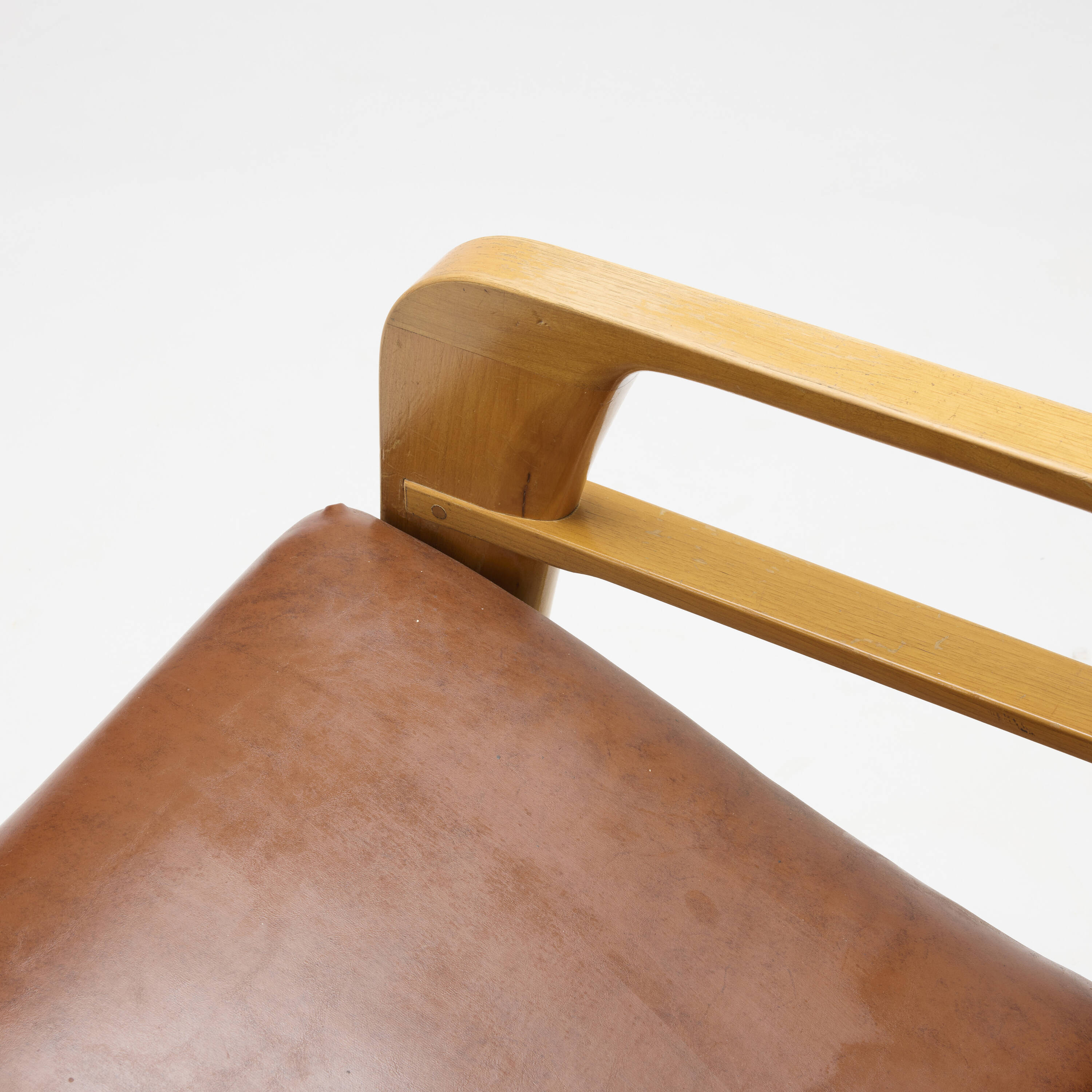 Close detail of the Airline Chair's bent wood arm and leather